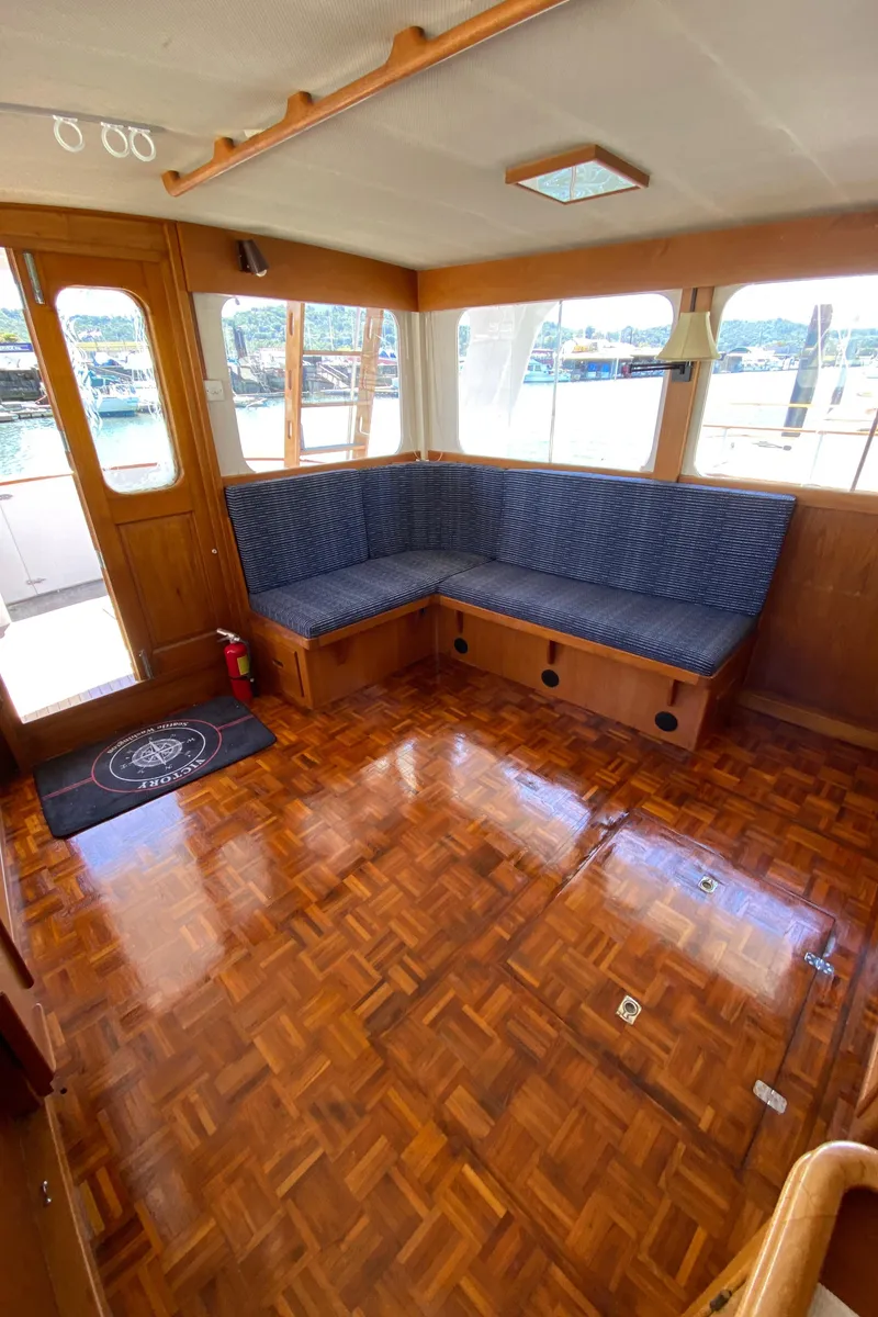 Slide: The Image of 1977 Grand Alaskan Raised Pilothouse interior with wood flooring and blue cushioned seating. - 40