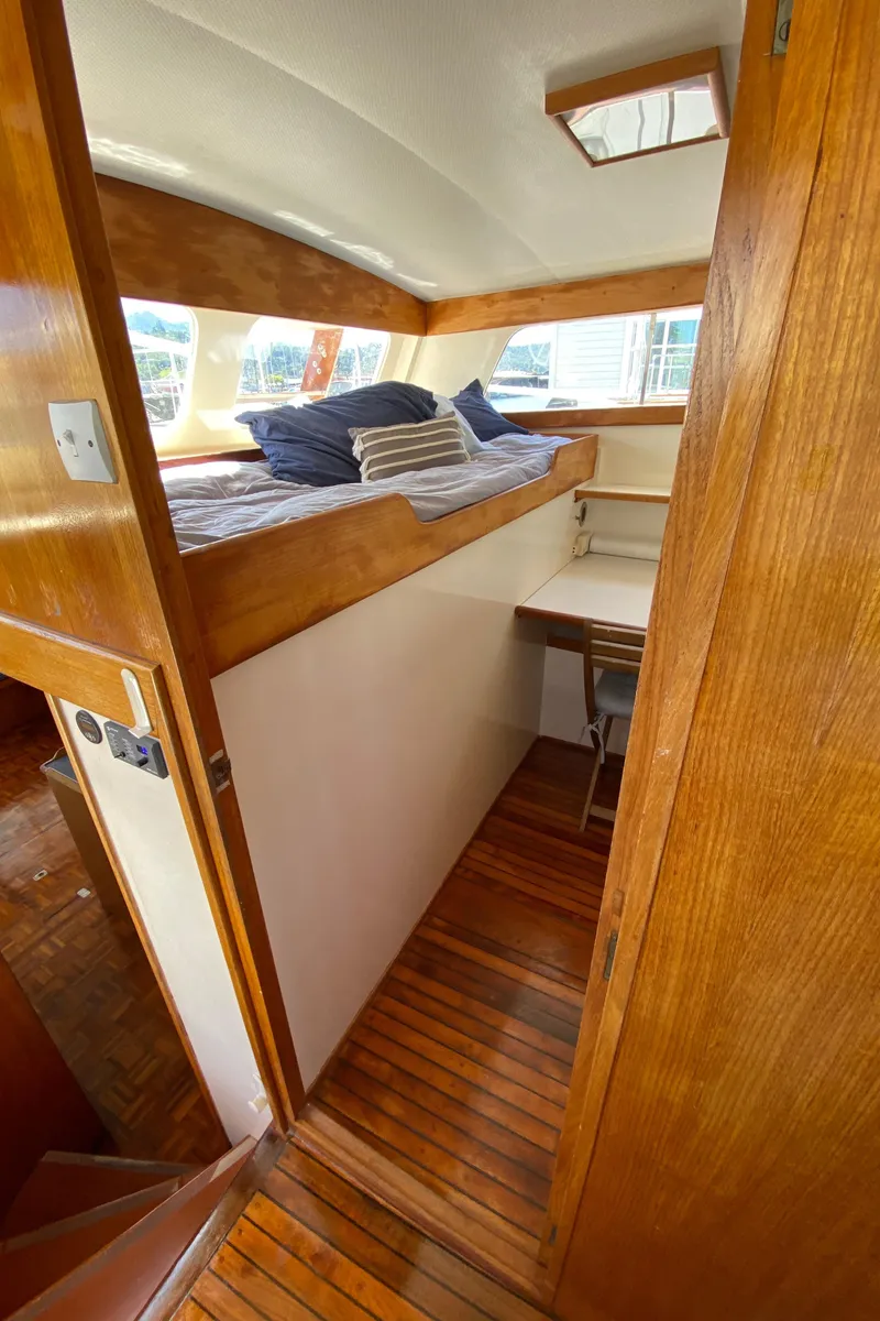 Slide: The Image of 1977 Grand Alaskan Raised Pilothouse interior with wooden finishes and cozy sleeping area. - 45