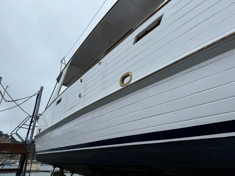 Slide: The Image of 1977 Grand Alaskan Raised Pilothouse yacht, white hull, docked at marina. - 48