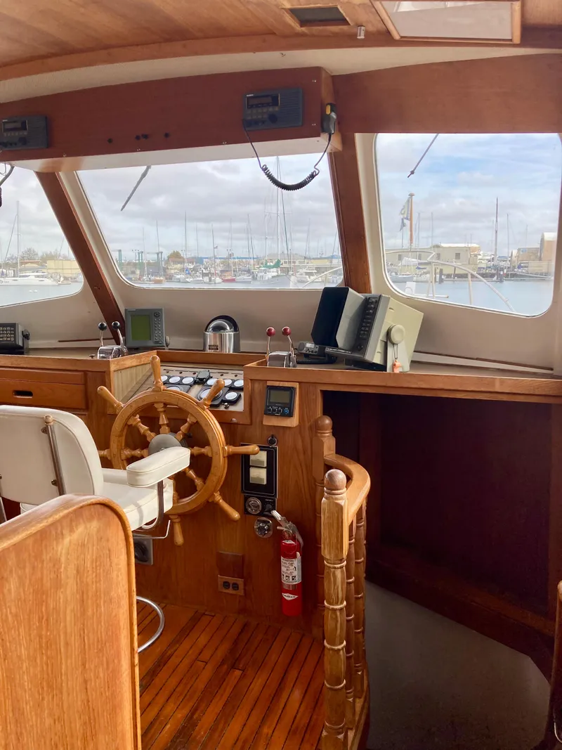 Slide: The Image of 1977 Grand Alaskan Raised Pilothouse interior with wooden helm and nautical instruments. - 9