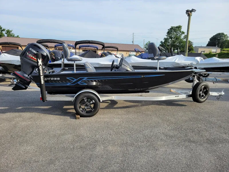 The Image of 2025 Xpress H17C Crappie boat in stock, black with blue accents, on trailer. - 1