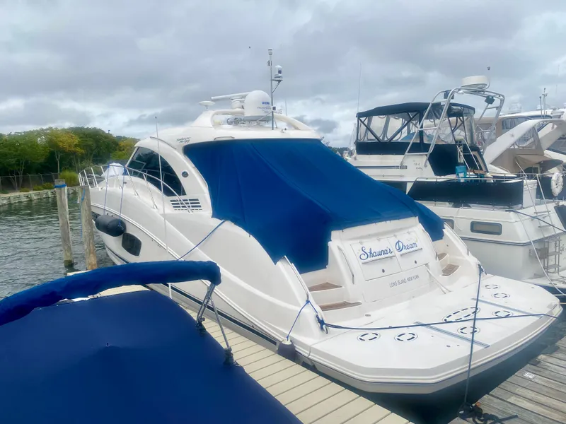 Slide: The Image of 2013 Sea Ray 580 Sundancer yacht docked with blue cover, overcast sky. - 9