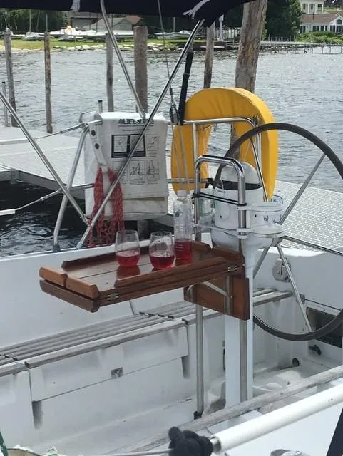 Slide: The Image of 1989 Beneteau First 285 sailboat cockpit with drinks on a wooden table, docked by the water. - 3