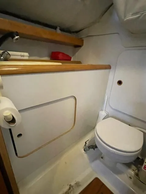Slide: The Image of Compact bathroom in a 1989 Beneteau First 285 sailboat, featuring a toilet and wooden accents. - 6