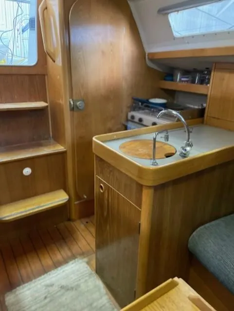 Slide: The Image of Interior of 1989 Beneteau First 285 sailboat with wooden cabinetry and compact kitchen area. - 9