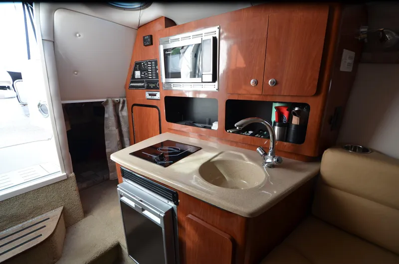 Slide: The Image of 2011 Crownline 280 CR boat interior with kitchenette, sink, and microwave. - 14