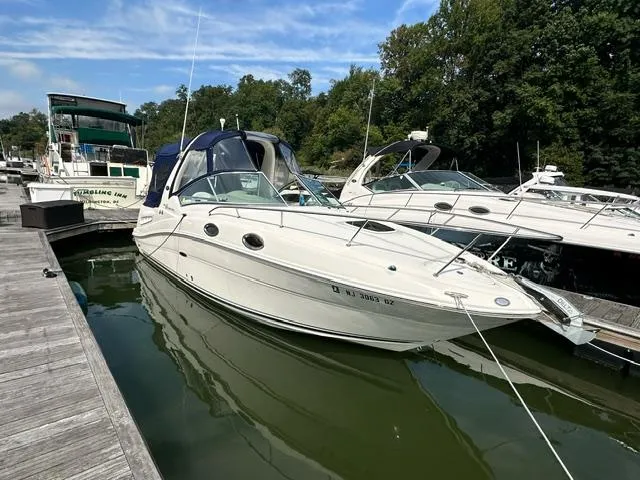 Slide: The Image of 2006 Sea Ray 260 Sundancer docked at marina, surrounded by trees and other boats. - 2
