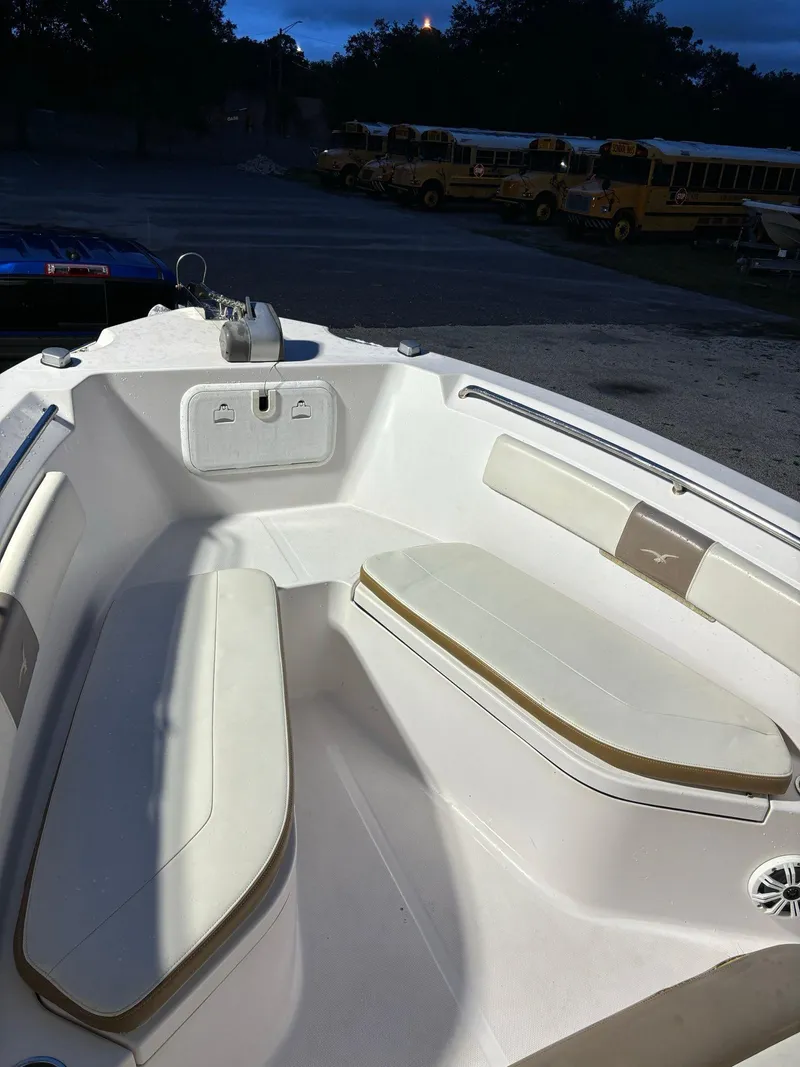 Slide: The Image of 2017 Pro-Line 23 Sport boat interior with cushioned seating, parked near school buses. - 21