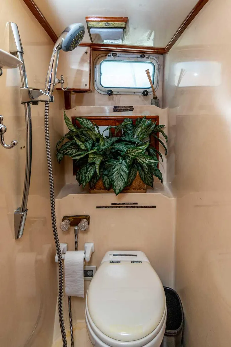 Slide: The Image of 1984 Marine Trader yacht bathroom with shower, toilet, and decorative plant. - 14