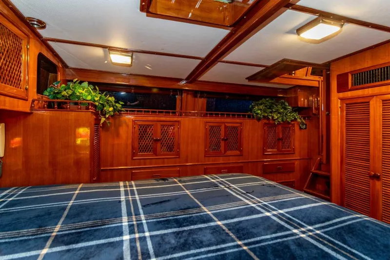 Slide: The Image of 1984 Marine Trader Aft Cabin Motor Yacht interior with wood paneling and plaid bedding. - 18