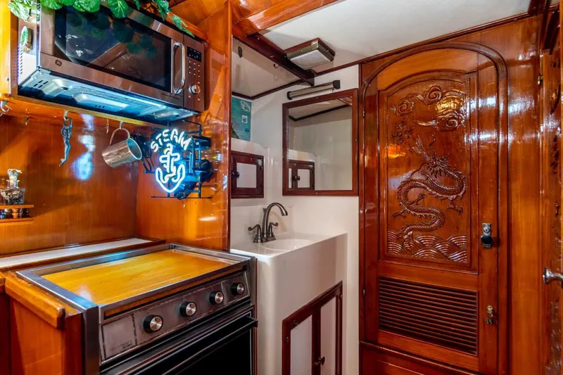 Slide: The Image of 1984 Marine Trader Aft Cabin Yacht interior with wood paneling, microwave, and decorative dragon door. - 21