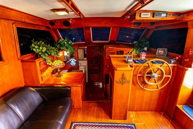 Slide: The Image of 1984 Marine Trader Aft Cabin Motor Yacht interior with wooden helm and cozy seating. - 23