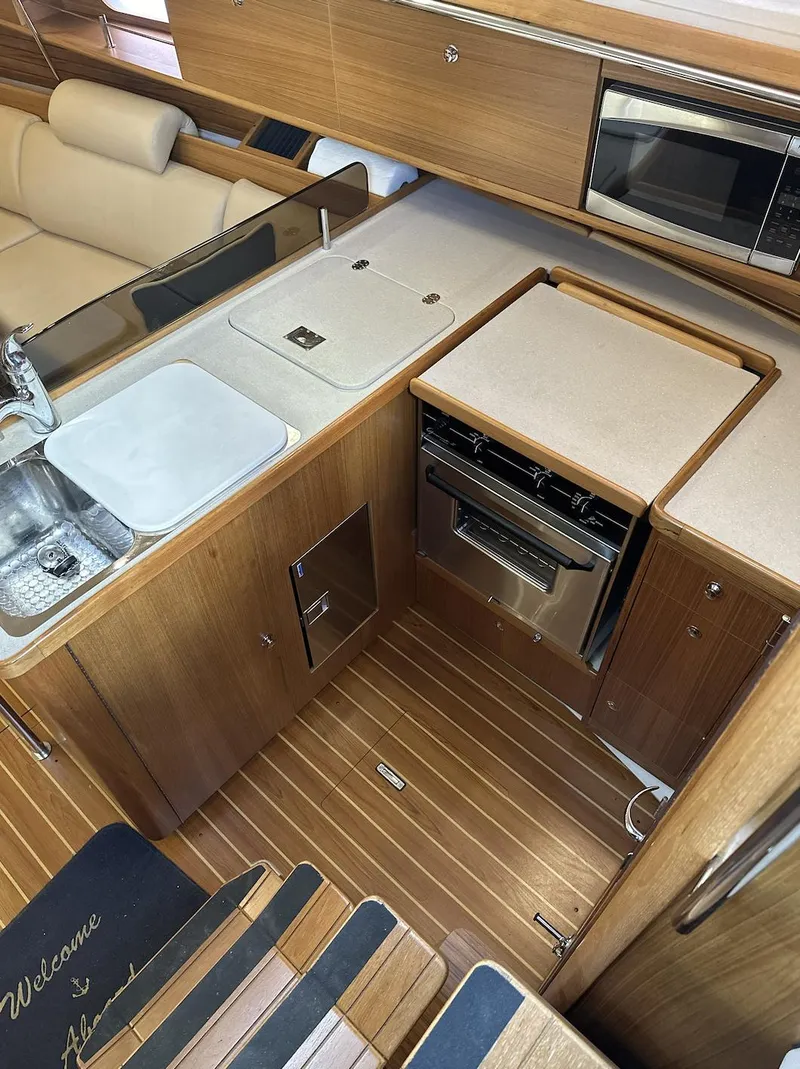 Slide: The Image of 2013 Catalina 355 yacht interior with modern kitchen, featuring wood cabinetry and stainless steel appliances. - 22