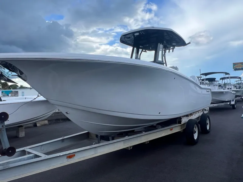 Slide: The Image of 2025 Tidewater 272 CC Adventure boat on trailer under cloudy sky. - 2