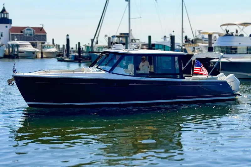 Slide: The Image of 2024 MJM 3 boat docked in marina, featuring sleek design and American flag. - 2