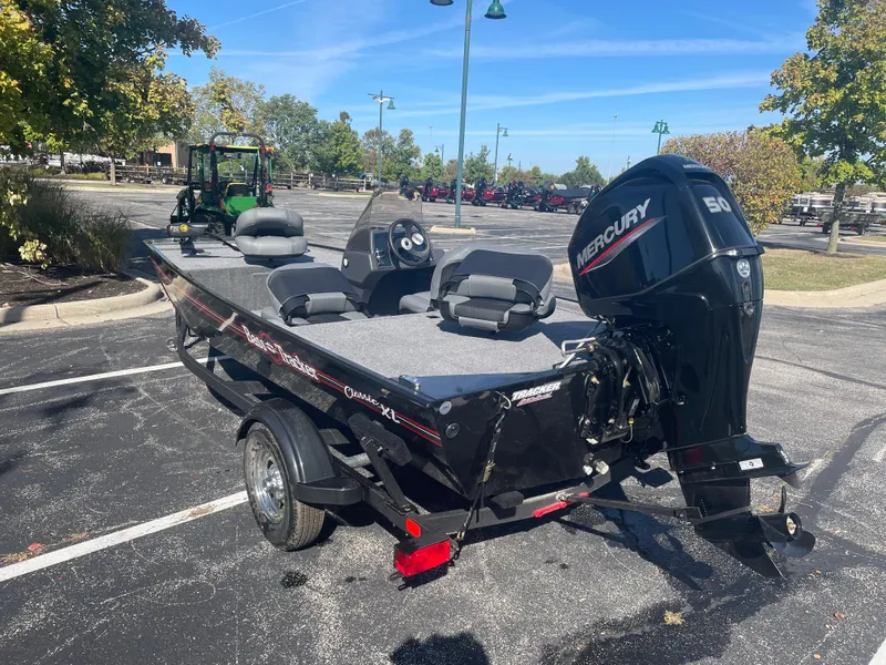 Slide: The Image of 2025 Tracker Bass Tracker Classic XL boat with Mercury engine in parking lot. - 2
