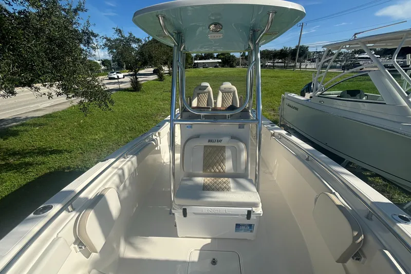 Slide: The Image of 2025 Bulls Bay 255CC boat interior with seating and console, parked on grass. - 11