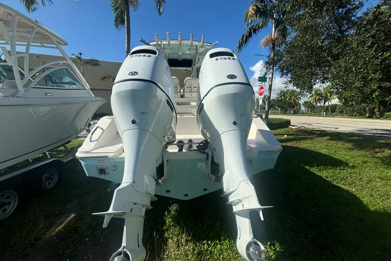 Slide: The Image of 2025 Bulls Bay 255CC boat with dual outboard motors, parked on grass. - 4