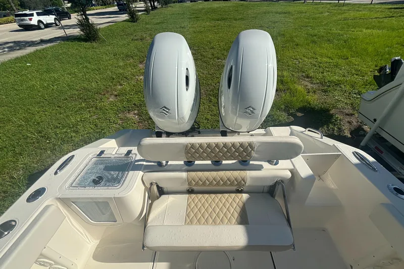 Slide: The Image of 2025 Bulls Bay 255CC boat with dual engines and cushioned seating, parked on grass. - 5