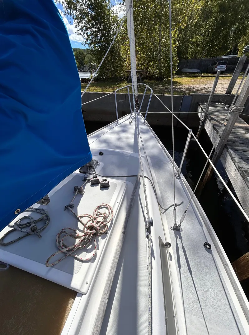 Slide: The Image of 1991 J Boats J/22 sailboat with blue sail, docked near lush greenery. - 10