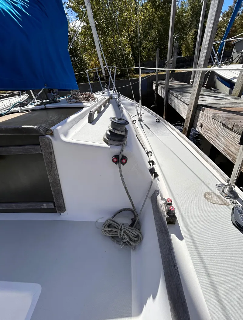 Slide: The Image of 1991 J Boats J/22 sailboat deck with winches and rigging, docked near trees. - 9