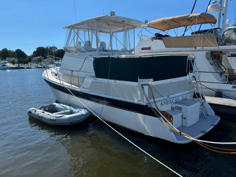 Slide: The Image of 2004 Nauset 33 boat docked with inflatable dinghy on calm water. - 2