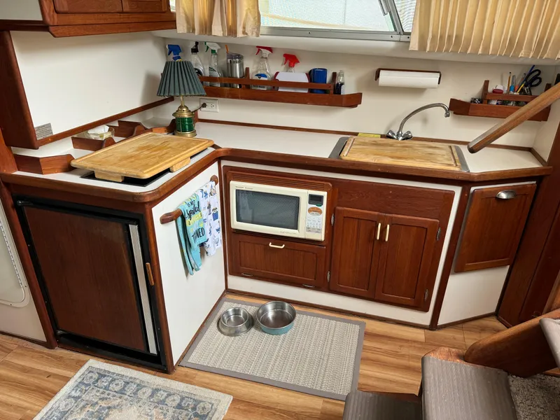 Slide: The Image of 2004 Nauset 33 boat kitchen with wood cabinets, microwave, and sink. - 24