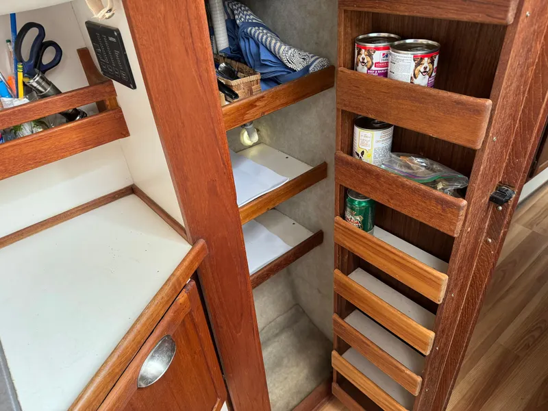 Slide: The Image of Wooden storage shelves in a 2004 Nauset 33 boat interior with canned goods and supplies. - 25