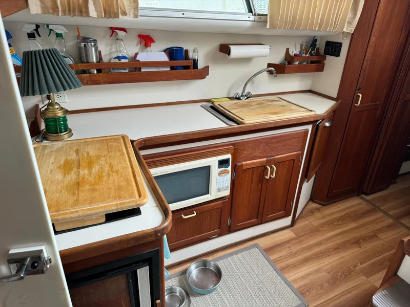 Slide: The Image of 2004 Nauset 33 boat kitchen with wooden cabinets, microwave, and sink. - 26