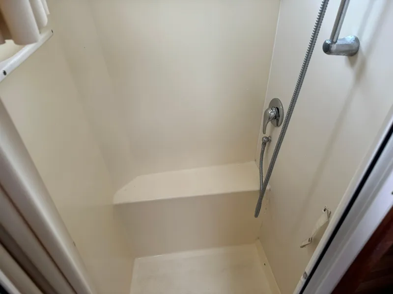Slide: The Image of Compact shower area in a 2004 Nauset 33 boat, featuring a handheld showerhead. - 35