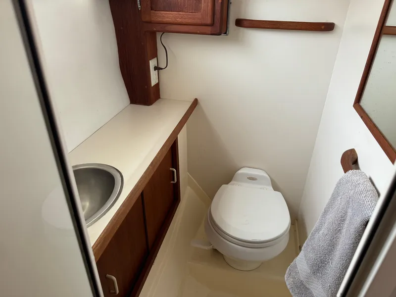 Slide: The Image of Compact boat bathroom with sink, toilet, and wooden cabinets in a 2004 Nauset 33 model. - 36