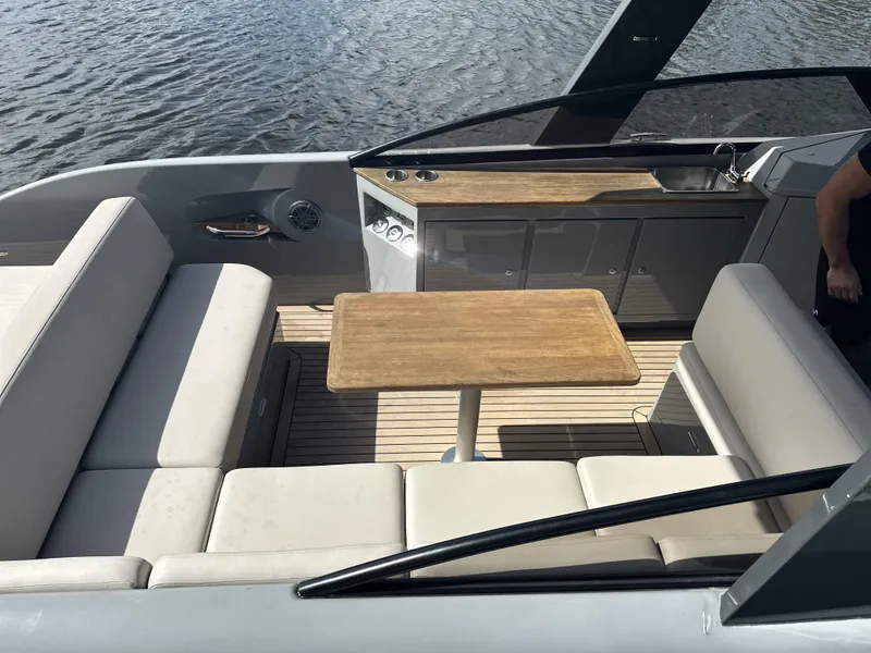 Slide: The Image of 2021 Rand Leisure boat interior with seating, table, and kitchenette on calm water. - 10