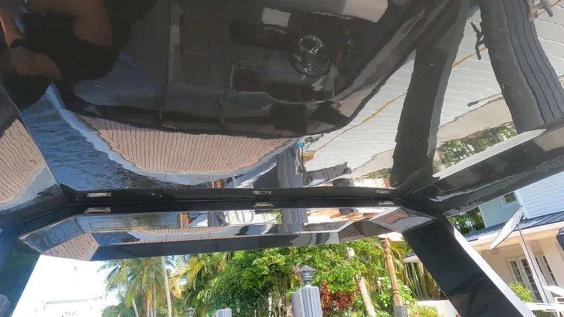 Slide: The Image of Sleek black Rand Leisure 2021 boat with reflective surfaces, docked near tropical greenery. - 44