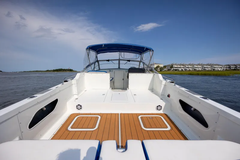 Slide: The Image of 1983 Bertram 28 Moppie boat with spacious deck and blue canopy on calm water. - 11