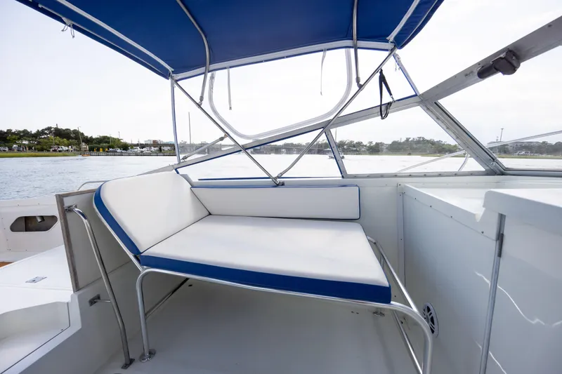 Slide: The Image of 1983 Bertram 28 Moppie boat interior with blue and white seating under canopy. - 17