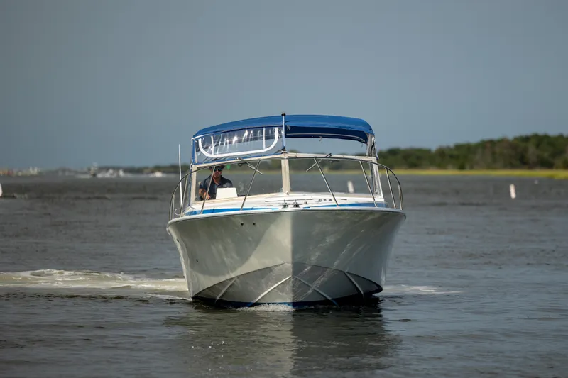 Slide: The Image of 1983 Bertram 28 Moppie boat cruising on open water with blue canopy. - 3