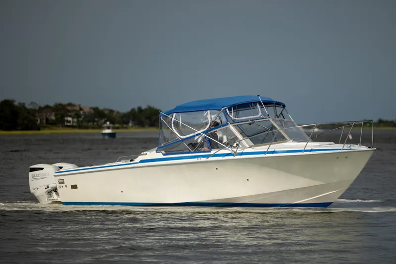 Slide: The Image of 1983 Bertram 28 Moppie boat cruising on calm waters with blue canopy. - 5