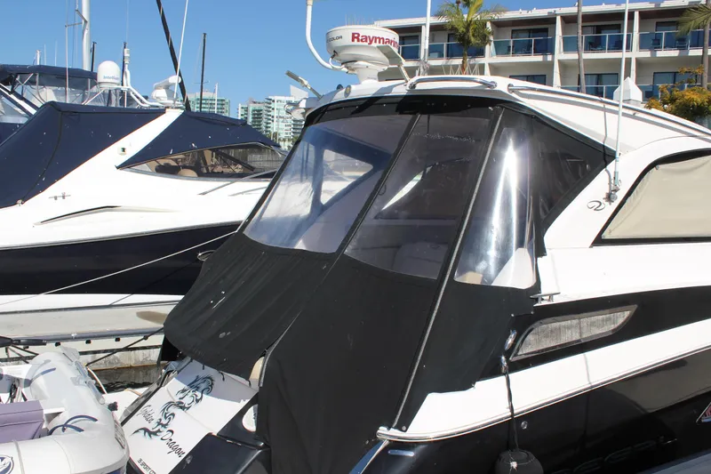 Slide: The Image of 2012 Regal 35 Sport Coupe yacht docked at marina, featuring sleek design and black canopy. - 16