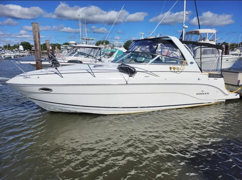 The Image of 2007 Rinker 300 Express Cruiser docked in a marina under blue skies. - 0