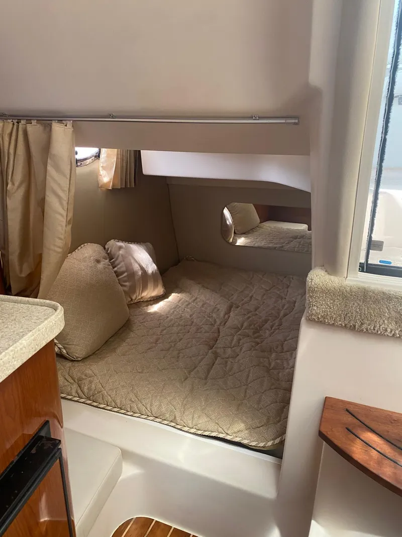 Slide: The Image of 2006 Regal 2860 Window Express cabin interior with cozy bed and natural light. - 13