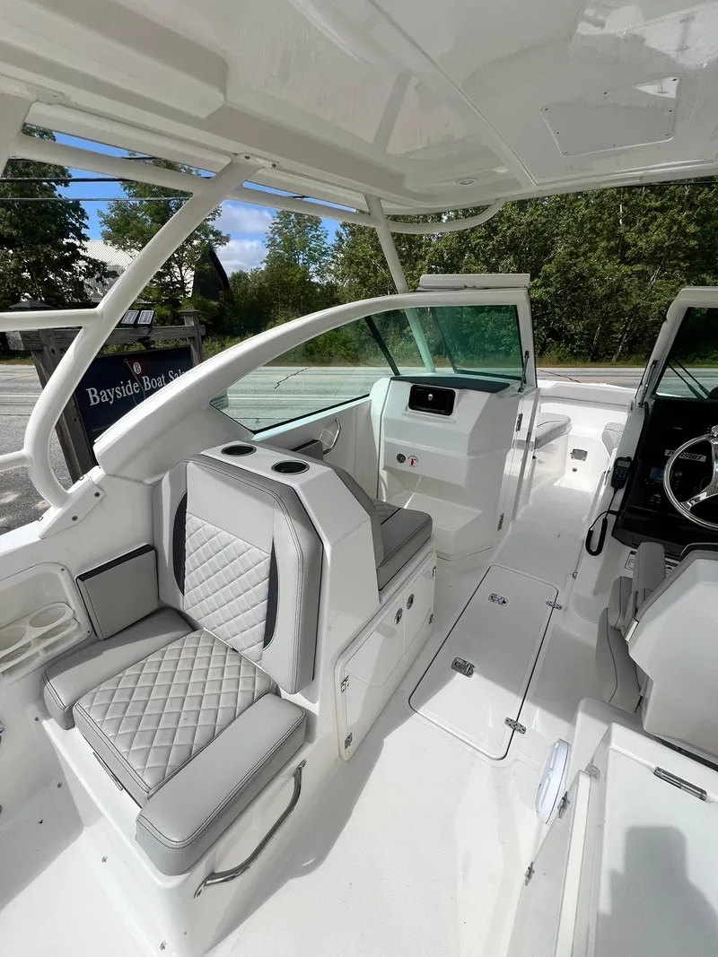 Slide: The Image of 2022 Pursuit DC 266 Dual Console boat interior with cushioned seating and modern dashboard. - 15