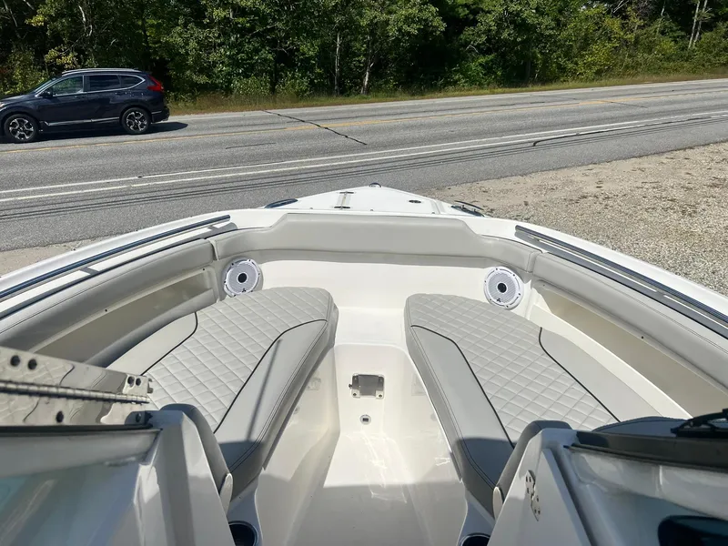 Slide: The Image of 2022 Pursuit DC 266 Dual Console boat interior with seating, parked near a road. - 24