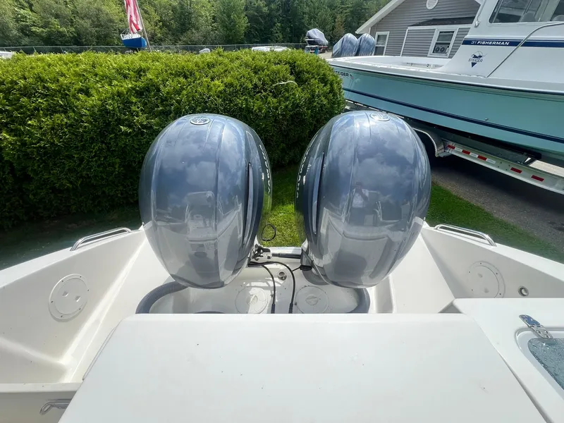 Slide: The Image of 2022 Pursuit DC 266 Dual Console with twin outboard motors, parked near greenery. - 32