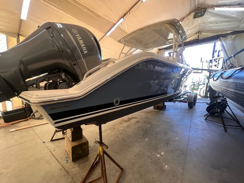 Slide: The Image of 2022 Pursuit DC 266 Dual Console boat in storage, featuring Yamaha outboard motor. - 39