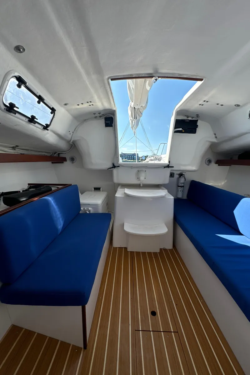 Slide: The Image of Interior of 2022 J Boats J/9 sailboat with blue seating and wooden flooring. - 12