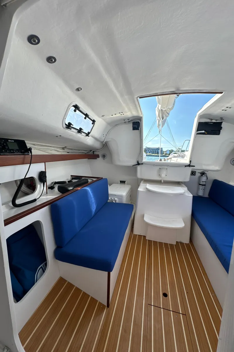 Slide: The Image of Interior of 2022 J Boats J/9 sailboat with blue seating and wooden flooring. - 13