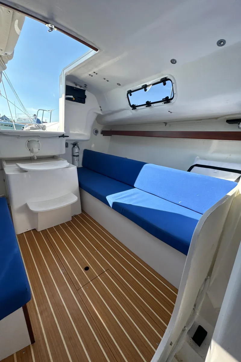 Slide: The Image of Interior of 2022 J Boats J/9 sailboat with blue seating and wood flooring. - 14