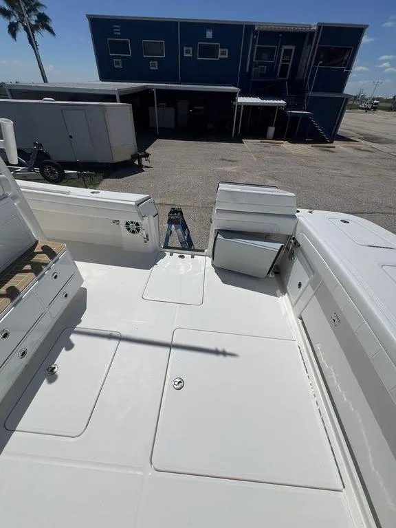 Slide: The Image of 2021 Regulator 41 boat deck with storage compartments and seating, docked near a blue building. - 21