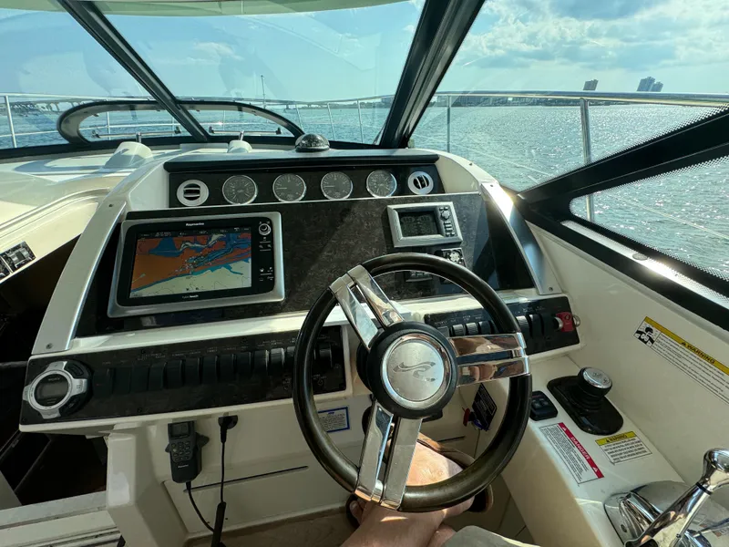 Slide: The Image of 2013 Sea Ray 410 Sundancer helm with navigation system and steering wheel, overlooking the ocean. - 14