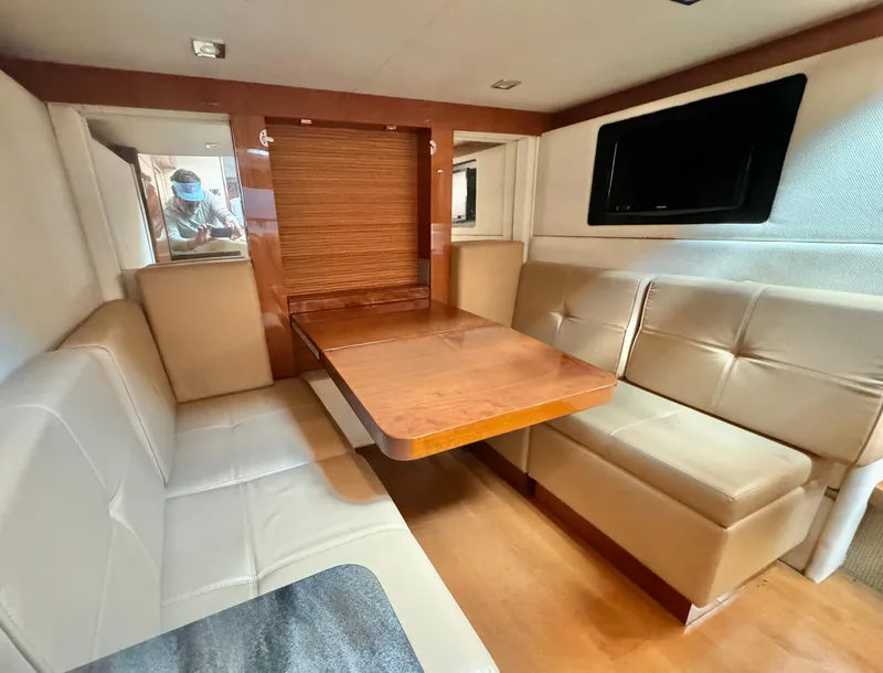 Slide: The Image of Interior of 2013 Sea Ray 410 Sundancer with beige seating and wooden table. - 23